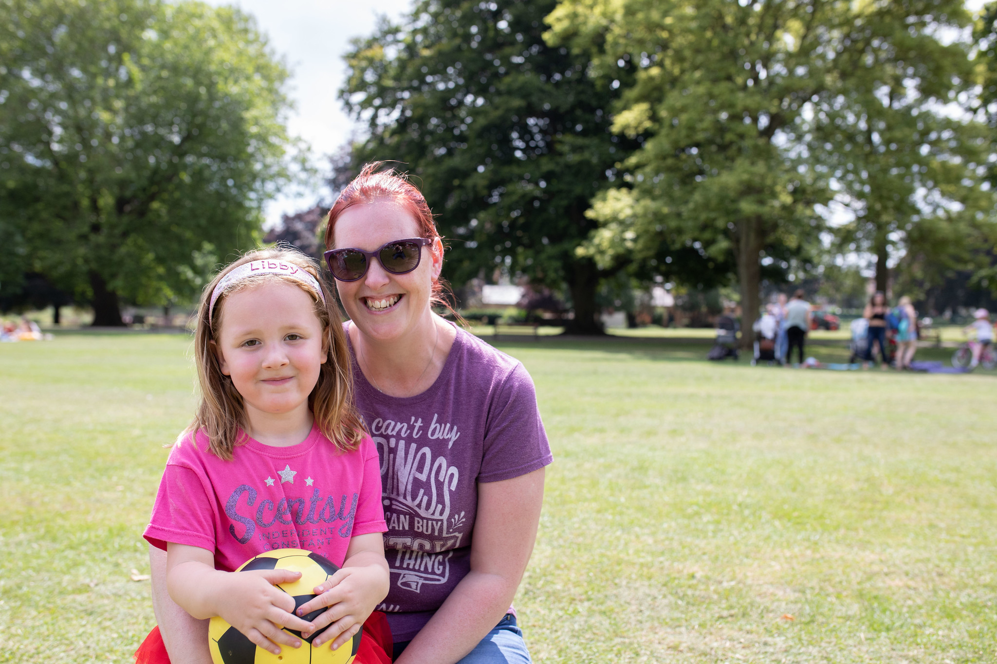 Mum and daughter in the park Mum kneeling down next to a young girl.