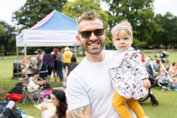 Man stood outside holding a young child