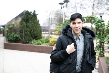 Male stood outside holding his bag