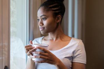 woman standing in front of a window holding a cup of tea